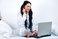 Happy woman with phone and laptop in bed Royalty Free Stock Photo