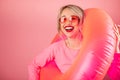 Happy woman in pink heart shaped sunglasses holding pink inflatable ring toy for the pool Royalty Free Stock Photo