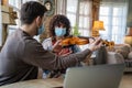 Happy woman play violin under music teacher's instructions in mask during coronavirus at home