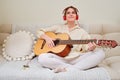 Happy woman playing acoustic guitar sitting at home in the living room Royalty Free Stock Photo