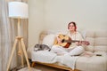 Happy woman playing acoustic guitar sitting at home in the living room Royalty Free Stock Photo