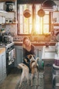 Happy woman playing with dogs in an old narrow cluttered kitchen at sunset