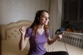 Happy woman playing video games, sitting on bed holding joystick