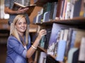 Happy woman, portrait and library book on shelf for reading, literature or learning knowledge at bookstore. Female Royalty Free Stock Photo