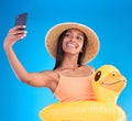 Happy woman, portrait smile and selfie on swimming vacation for profile picture with inflatable duck against a blue Royalty Free Stock Photo