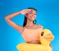 Happy woman, portrait smile and swimming vacation in salute standing with inflatable duck against a blue studio