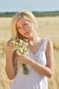 Happy woman posing with camomile in golden wheat. Royalty Free Stock Photo