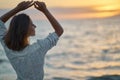 Happy woman posing with hands up to the sky, enjoying sunset over the sea Royalty Free Stock Photo