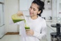 Happy woman pouring healthy juice into a glass