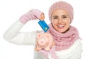 Happy woman putting credit card in piggy bank