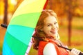 Happy woman with rainbow multicolored umbrella under rain in par