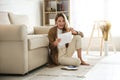 Happy woman reading letter while sitting on floor near sofa at home Royalty Free Stock Photo