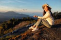 Woman reading a map siting on green grass meadow on top of mountain and enjoying nature ,sunrise in winter Royalty Free Stock Photo