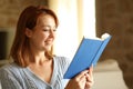 Happy woman reading a paper book seated at home Royalty Free Stock Photo