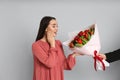 Happy woman receiving red tulip bouquet from man on light grey background. 8th of March celebration Royalty Free Stock Photo