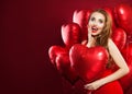 Happy woman in red dress holding balloons red heart on red banner background. Cheerful surprised girl with red lips makeup Royalty Free Stock Photo