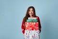 Happy woman red sweater holding boxes. Girl with gifts in hand smiling over blue background. Royalty Free Stock Photo