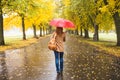 Happy woman with red umbrella walking at the rain in beautiful autumn park. Royalty Free Stock Photo