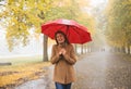 Happy woman with red umbrella walking at the rain in beautiful autumn park Royalty Free Stock Photo