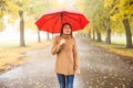 Happy woman with red umbrella walking at the rain in beautiful autumn park. Royalty Free Stock Photo