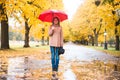 Happy woman with red umbrella walking at the rain in beautiful autumn park. Royalty Free Stock Photo