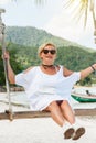 Happy woman relaxing with hanging swing on tropical beach Royalty Free Stock Photo