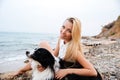 Happy woman relaxing with her dog on the beach Royalty Free Stock Photo