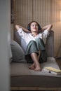 Happy woman relaxing in her sofa at home, Smiling girl is listening to music with headphones and lying down with eyes Royalty Free Stock Photo