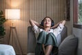 Happy woman relaxing in her sofa at home, Smiling girl is listening to music with headphones and lying down with eyes Royalty Free Stock Photo