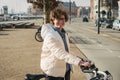 Happy woman renting bicycle at public urban cycle transport station in Copenhagen, Denmark. Young woman taking a shared bicycle.