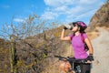 Happy woman riding a mountain bike getting hydrated, enjoying a summer day in the mountains Outdoor sports activity, lifestyle Royalty Free Stock Photo