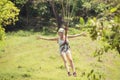 Happy woman riding a zip line in a lush tropical forest Royalty Free Stock Photo