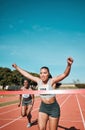 Happy woman, running and winning by finish line in race, competition or marathon on outdoor stadium track. Female person Royalty Free Stock Photo