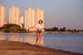 A happy woman runs freedom along the beach. A smiling beautiful blonde in a white shirt and denim shorts is spinning in Royalty Free Stock Photo