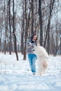 Happy woman with Samoyed dog in winter forest Royalty Free Stock Photo