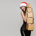 Happy woman in santa hat holding many gifts boxes. Royalty Free Stock Photo