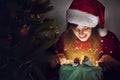 happy woman in santa hat opening gift box at christmas tree lights. magic light. surprise. space for text. merry christmas and ha Royalty Free Stock Photo