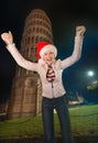 Happy woman in Santa hat rejoicing near Leaning Tower of Pisa Royalty Free Stock Photo