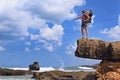 Happy woman on sea cliff with child in backpack carrier