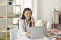 Happy woman seamstress or fashion designer sitting at laptop looking for new ideas.