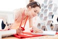 Happy woman seamstress at work with red fabric