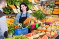 Happy seller helping customer to buy vegetables Royalty Free Stock Photo