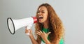 Happy woman, shouting and pointing with megaphone for motivation on a gray studio background. Excited female person Royalty Free Stock Photo