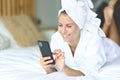 Happy woman after showering using mobile phone