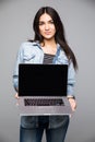 Happy woman showing blank laptop screen over gray background. Royalty Free Stock Photo