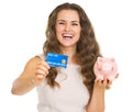 Happy woman showing credit card and piggy bank