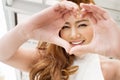 Happy woman showing heart hand sign to you