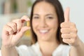 Happy woman showing a vitamin pill with thumbs up Royalty Free Stock Photo