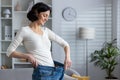 Happy woman showing weight loss by wearing old jeans at home Royalty Free Stock Photo