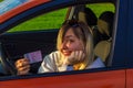 A happy woman sits behind the wheel of a car and shows her new driver& x27;s license. A woman is smiling cutely Royalty Free Stock Photo